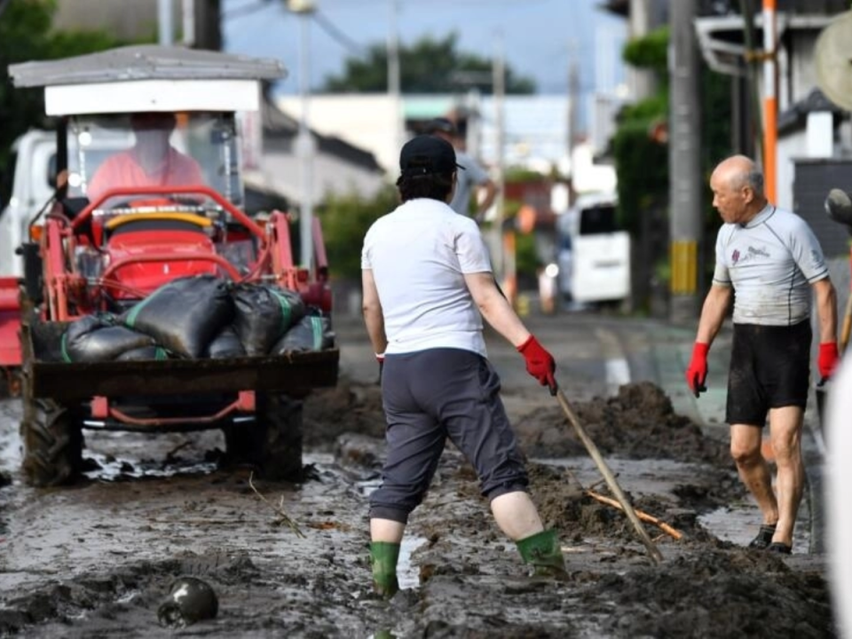 Residentes en la ciudad japonesa de Kurume limpian el barro en una carretera, tras las intensas lluvias.
