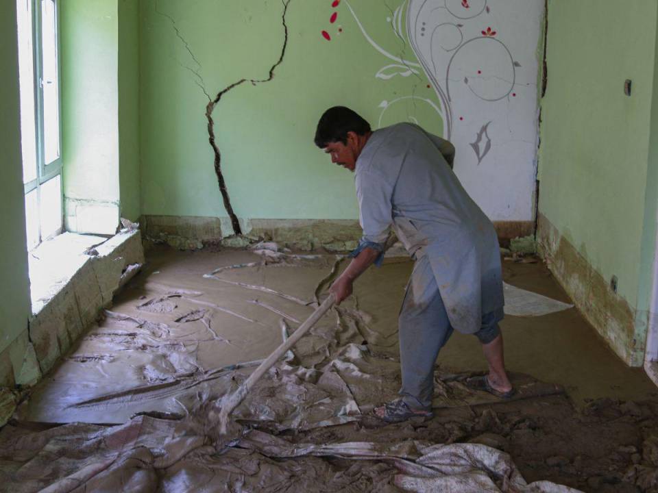 Un hombre afgano limpia los escombros y el barro de su casa luego de las inundaciones repentinas en el área de Khair Abad en la provincia de Ghazni el 23 de julio de 2023.