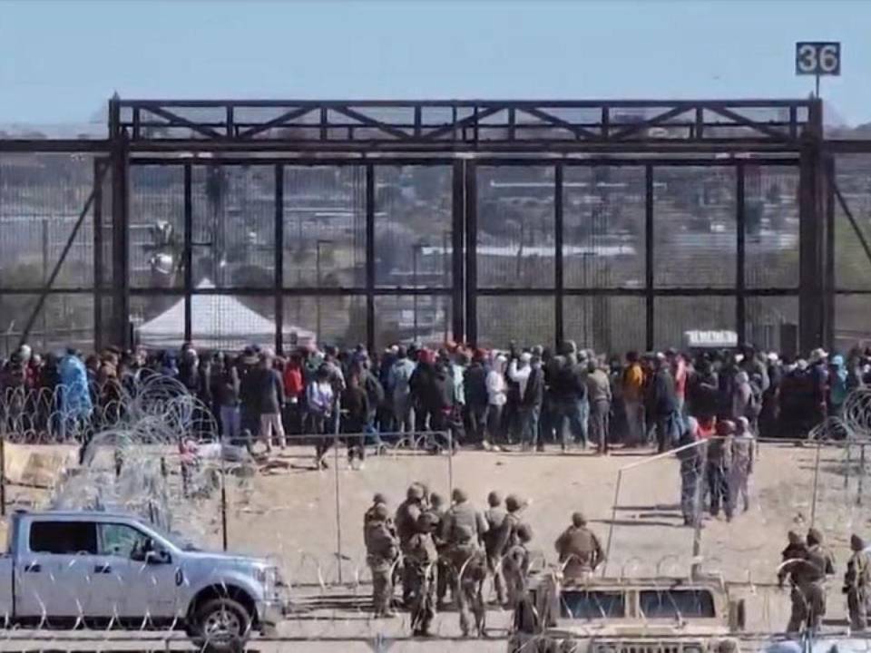 A pesar de los esfuerzos de algunos militares por contenerlos, los migrantes lograron superar la barricada y corrieron hacia el muro de metal cerrado.