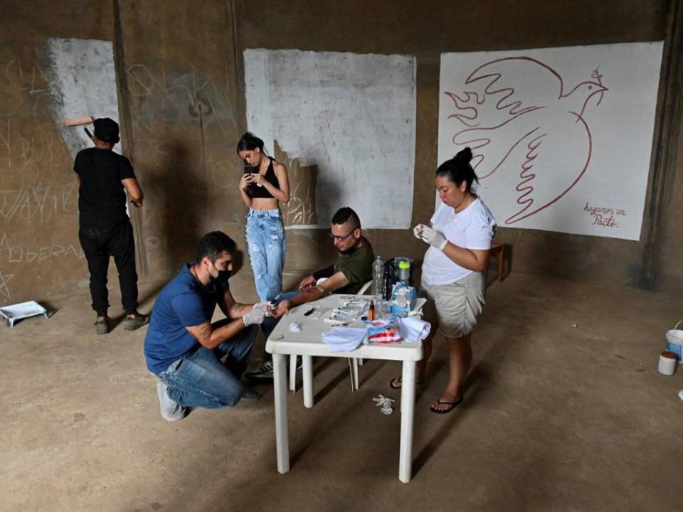 A un voluntario le extraen sangre del brazo para que el artista colombiano Julián Castillo la use para pintar un mural que representa al cantante puertorriqueño René Pérez.