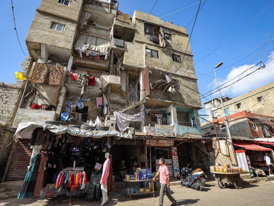 Un hombre camina afuera de una tienda de ropa a lo largo de un callejón en el campamento de Shatila para refugiados palestinos en el suburbio sur de Beirut el 7 de noviembre de 2023 en medio de batallas en curso entre Israel y el grupo militante palestino Hamás en la Franja de Gaza.