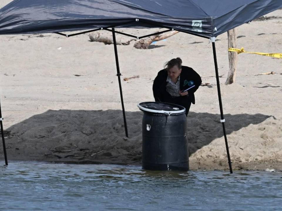 Un funcionario se para junto a un barril donde se descubrió un cuerpo en Malibu Lagoon State Beach, California.