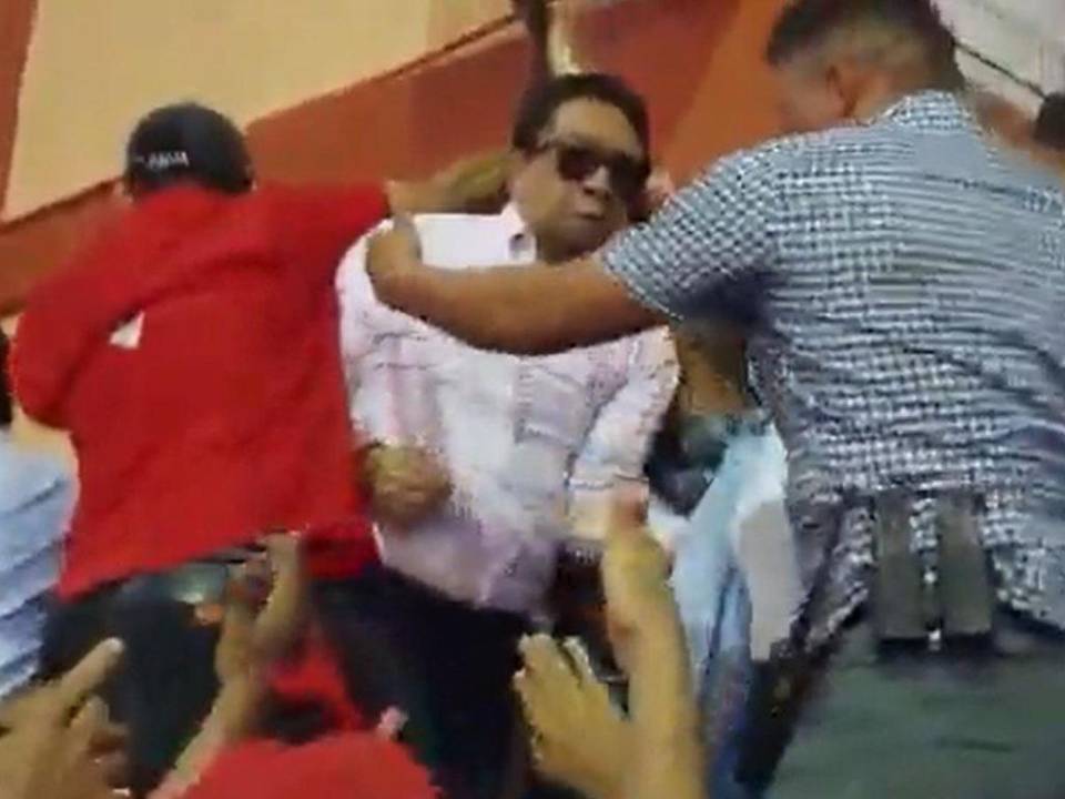Con empujones y hasta puñetazos, militantes de Libre intentan sacar al diputado Ramón Barrios del estrado principal.