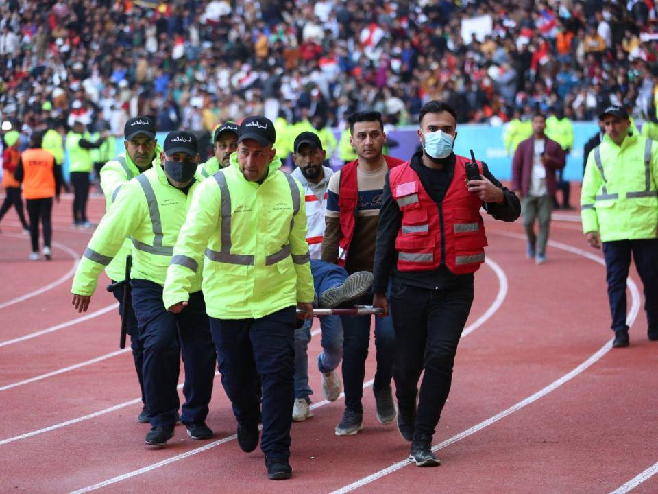 Un grupo de miembros de la seguridad trasladan a un herido al area de emergencias del Estadio Internacional de Basora.