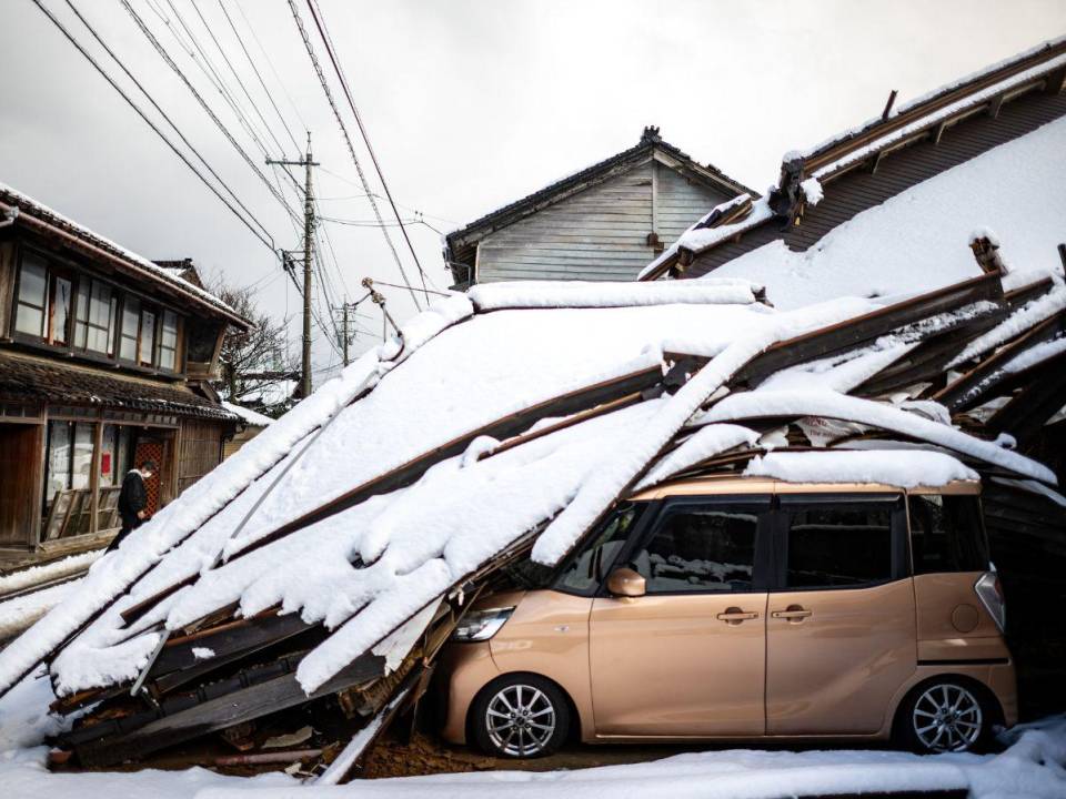 Un automóvil dañado yace debajo de un edificio derrumbado en la ciudad de Shika en el distrito de Hakui, prefectura de Ishikawa, el 8 de enero de 2024, después de que un gran terremoto de magnitud 7,5 sacudiera la región de Noto el día de Año Nuevo.