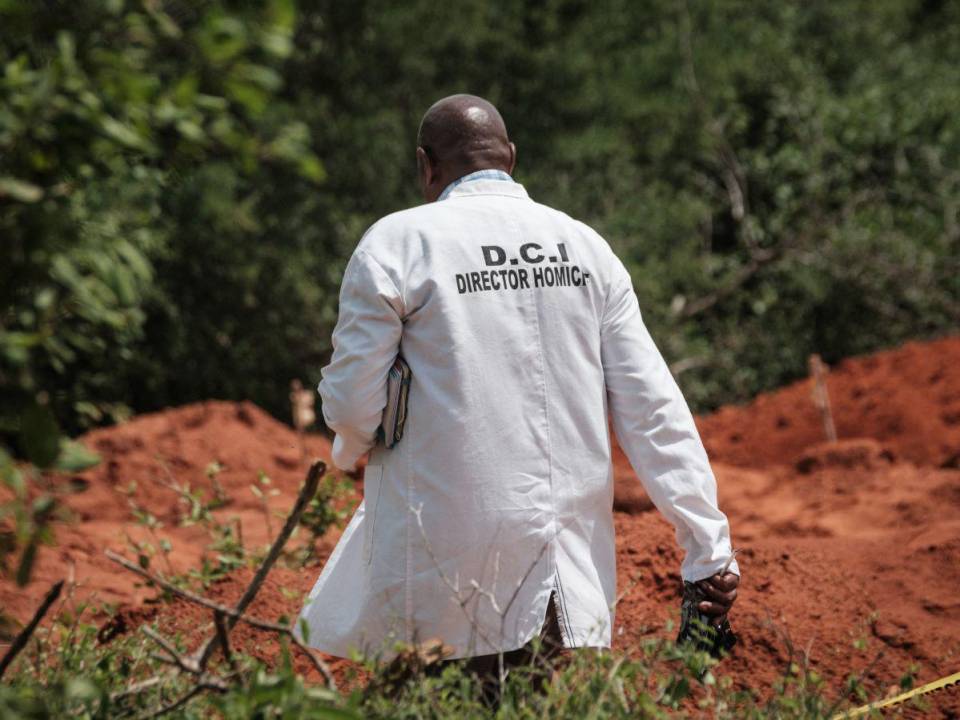 Un oficial de la Dirección de Investigaciones Criminales de Kenia (DCI) camina junto al terreno excavado en el sitio de fosas comunes en Shakahola.